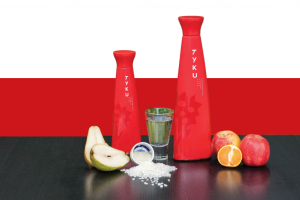 a group of red bottles next to a glass of water and fruit