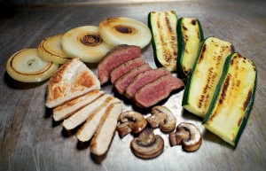 a group of sliced meat and vegetables on a table
