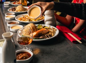 a person pouring sauce on a plate of food